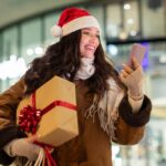 Excited,Smiling,Woman,In,Santa,Hat,Walking,Near,Mall,In
